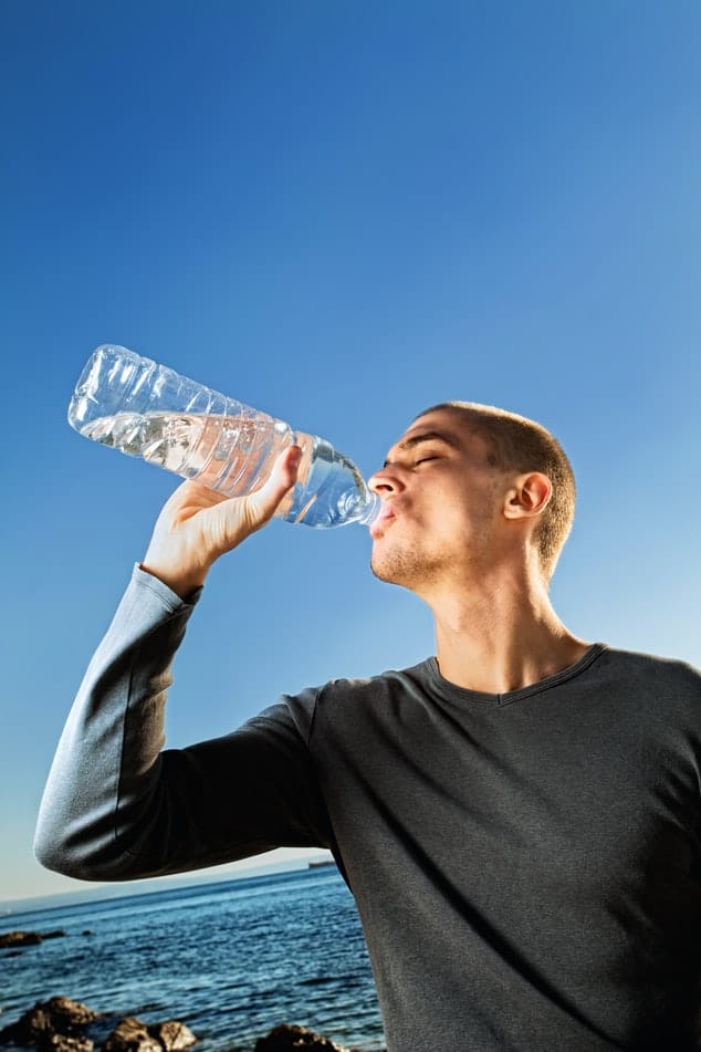Man drinking bottled water by the ocean